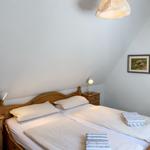 Schlafzimmer mit Doppelbett, Holzmöbel und Stehlampe. Decke geneigt, Wandbild mit Schafen.