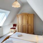 Schlafzimmer mit Dachschrägen, Bett, Kleiderschrank, Stuhl und Dachfenster.