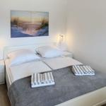 Bedroom with double bed, two nightstands, and wall art. Towels on bed.