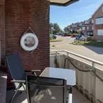 Balcony with table, two chairs, and a lifebuoy on the wall.