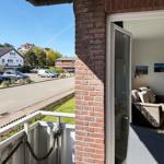 Terrace with view of street and parking lot. Entrance to living room with sofa and wall pictures.