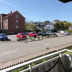 View of parking lot with cars and surrounding houses under blue sky.