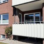 Single-family house with balcony, red brick, and white windows.