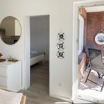 Living area with bedroom and balcony. Round mirrors and wooden furniture.