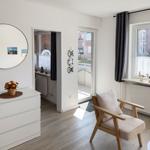 Living room with chair, window, cabinet, and mirror on the wall.