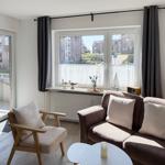 Living room with sofa, chair, and view of residential area.
