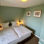 Schlafzimmer mit Bett, Nachttischen und Bildern an der Wand.