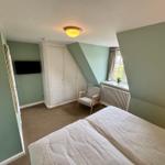 Schlafzimmer mit Dachschräge, Bett, Kleiderschrank und Fenster.