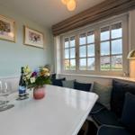 Esszimmer mit Fensterblick, Tisch, Stühle und Blumen.