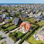 Aerial view of a coastal town with traditional houses and green lawns near the sea.