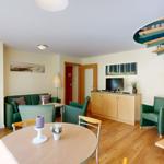 Wohnung mit Essbereich, Sofa, Fernseher und Wendeltreppe.