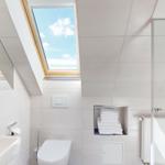 Badezimmer mit Dachfenster, Toilette, Waschbecken und Dusche.