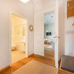 Flur mit Blick in Bad und Wohnbereich, Holzboden und Kleiderschrank mit Haken.