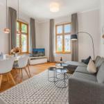 Wohn- und Essbereich mit Sofa, Tisch, Stühlen und Fenstern.