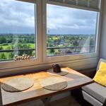 Tisch mit Platzset und Aussicht auf grüne Landschaft.
