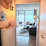 Wohnung mit Blick auf die Stadt. Wohnzimmer mit Sofa, Couchtisch und Balkon.