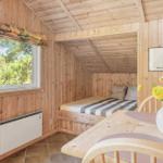 Schlafzimmer mit Holzwand, Bett und Fenster. Tisch mit Blumen und Stühlen.