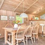 Holzgetäfelte Küche mit Esstisch, Stühlen und Barhocker. Wandbilder und Fenster sichtbar.