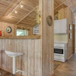 Küche mit weißen Geräten und Holzwand. Barbereich mit zwei Stühlen.