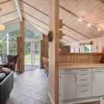 Küche mit Arbeitsplatte, Kühlschrank und Küchenzeile. Wohnbereich mit Sofa und Sicht auf Außenbereich.