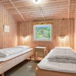Zwei Betten in einem holzverkleideten Raum mit Fenster und Nachttisch.