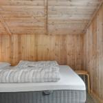 Schlafzimmer mit Holzwandverkleidung, Bett und Fenster