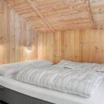 Schlafzimmer mit Holzwänden und Bett mit weißer Bettwäsche.