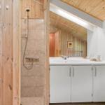 Bad mit Dusche, Waschbecken und Spiegel. Holzwände und -decke.