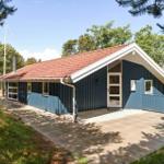 Ein blau gestrichenes Haus mit rotem Dach und weißer Tür. Umgeben von Bäumen und einem gepflasterten Weg.
