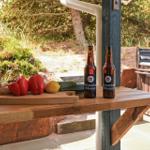 Holztisch mit Gemüse und Bierflaschen im Außenbereich