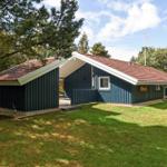 Ein blaues Ferienhaus mit rotem Dach, umgeben von Bäumen und Gras.