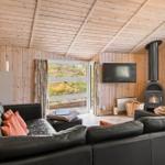 Wohnzimmer mit Sofa, Kamin und TV. Holzwände und -decke. Blick auf Garten.