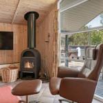 Raum mit Holzwand, Kaminofen, Fernseher und braunem Sessel.