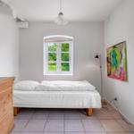 Schlafzimmer mit Bett, Schrank und Fenster zum Garten.