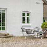 Haus mit weißer Fassade, Terrasse und Sitzgruppe. Thatched roof house im Hintergrund.