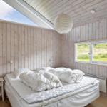 Schlafzimmer mit Holzwand, Bett und Fenster zum Grasland.