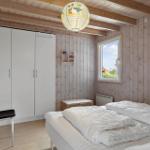 Schlafzimmer mit Holzwand, Bett, Kleiderschrank und Fenster.