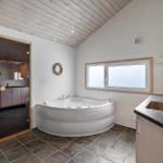 Badezimmer mit Dusche, Whirlpool und Fenster. Holzdecke und Fliesenboden.