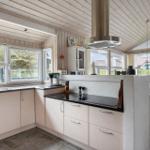 Küche mit Arbeitsfläche, Spüle und Fenstern zum Garten. Essbereich mit Tisch und Stühlen.