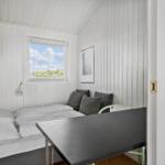 Zimmer mit Bett, Tisch und Fenster mit Blick auf Grün.