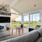 Wohnzimmer mit Sofa, Fernseher und Blick auf die Landschaft.
