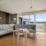 Wohnzimmer mit Sofa, Tisch und Terrasse. Holzboden und Backsteinwand.