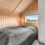 Schlafzimmer mit Holzwand, Bett und Fenster mit Blick auf Grün.