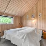 Schlafzimmer mit Holzwänden, Bett, Nachttisch und Fenster.