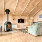 Wohnzimmer mit Kaminofen, Sofa und Fernseher an Holzwand