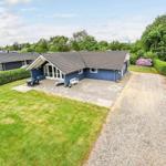 Blau gestrichenes Ferienhaus mit Terrasse und Garten. Gravelweg führt zum Eingang.