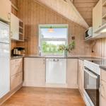 Küche mit Holzwänden, weißer Kühlschrank, Spülmaschine und Fenster mit Blick nach draußen.
