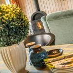 Tisch mit Geschirr, Pflanze und Kamin im Hintergrund.