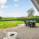 Terrasse mit Tisch und Stühlen, Blick auf grünen Rasen und Hecke.