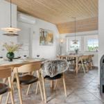Essbereich mit Holztisch, Stühlen und Kaminofen. Holzdecke und Wandbilder sichtbar.